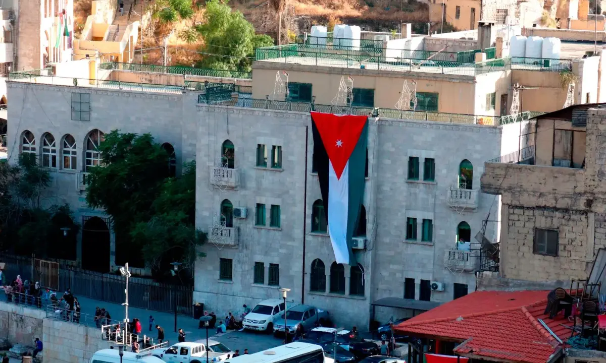 An Amman street with vehicles, buildings and Jordanian flags