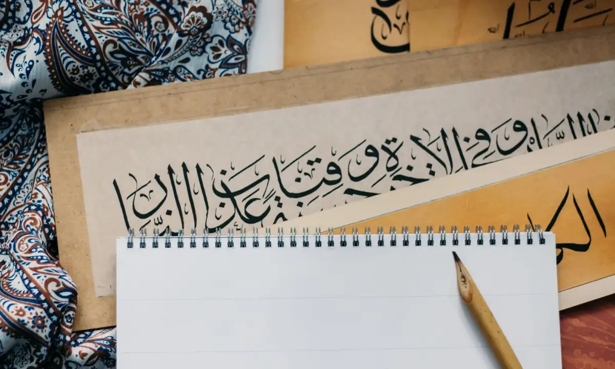 A notepad beside Arabic calligraphy