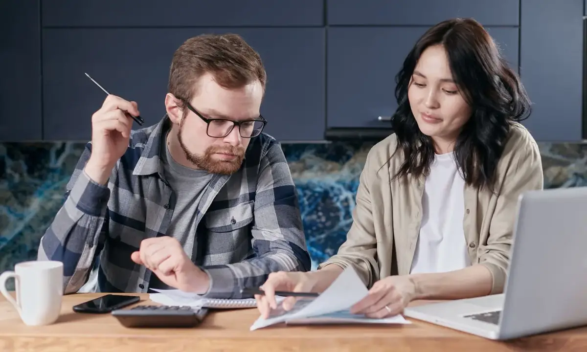 Two people reviewing household paperwork with a calculator